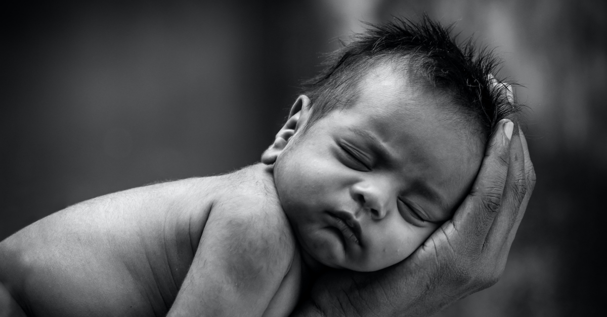 novorođenče spava u šaci majke